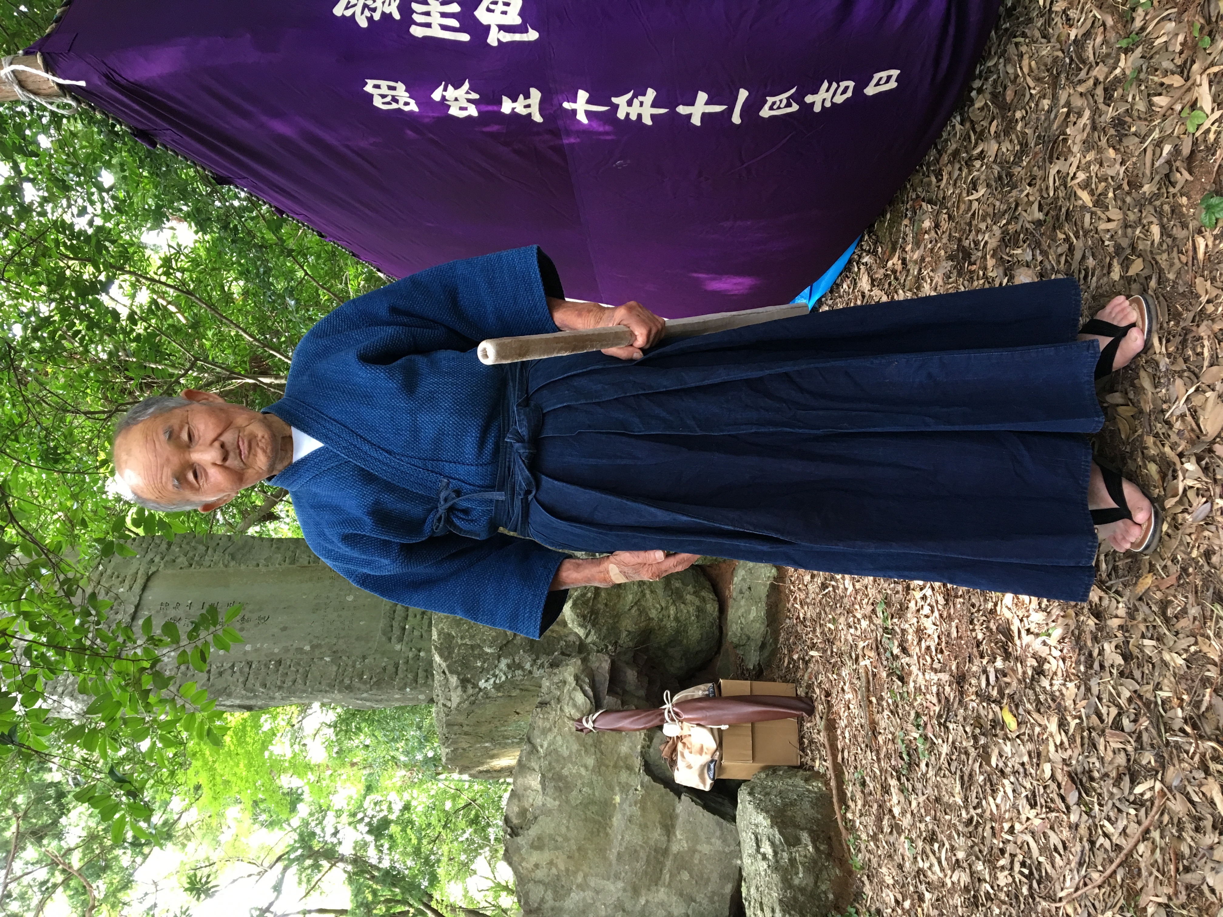 A person standing outdoors with a training implement beside a displayed banner